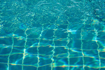 Clear water surface with ripple wave splashes in swimming pool. Summer abstract reflection caustics background.
