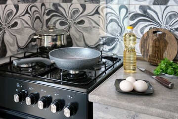 Empty non-stick frying pan eggs herbs and butter on the table of a home kitchen.