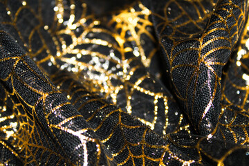 gold spider web on black mesh fabric. great for Halloween background or texture