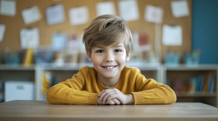 Naklejka premium cute schoolboy sitting at the desk, smiling, looking at the camera during the lesson