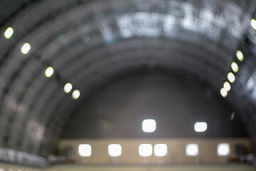 A blurred view of an arched interior ceiling, where the soft focus transforms the lights and structure into an abstract, almost dreamlike composition. The glow of the lights adds a sense of warmth and