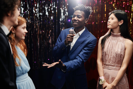 Group of individuals gathered at formal event with a person holding microphone