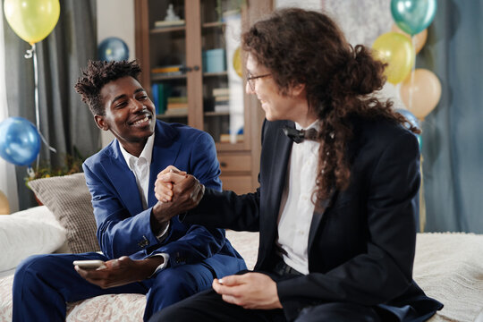 Two friends in formal attire sitting on couch in a cozy living room environment