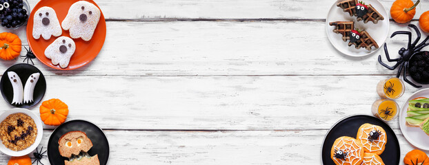 Spooky Halloween breakfast double border over a white wood banner background with copy space. Top view. Selection of pancakes, toast, oatmeal and fruit.