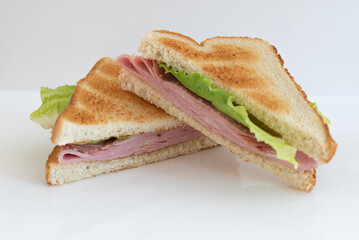 A mortadella toasted sandwich cut in half on a white background