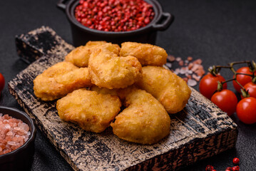 Delicious fresh crispy chicken nuggets on a dark concrete background