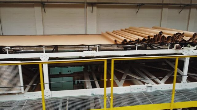 Ecological biodegradable package from recycled materials. Technological process of unwinding roll of kraft paper in cardboard production workshop at factory. Production cardboard packaging for goods.