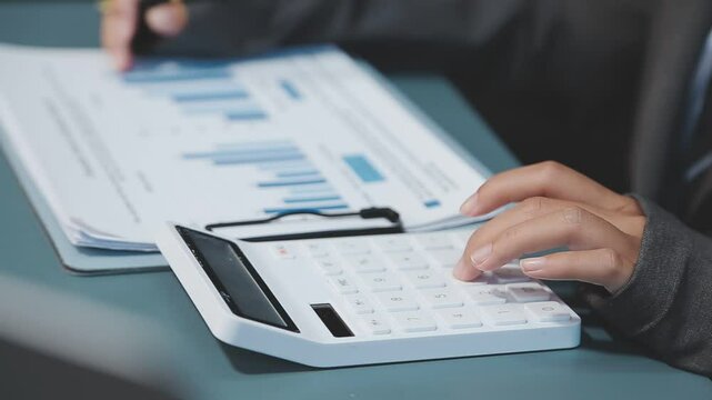 Business and Financial Planning Concept. Financial advisor hand planning and calculate budget, and tax. Professional Businesswoman use calculator and review annual report at home office.