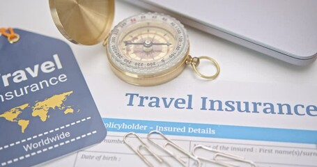 Travel insurance and service concept : Top view of travel insurance application form, an insurance tag, a compass, a laptop. Travel insurance covers costs and losses associated with traveling.