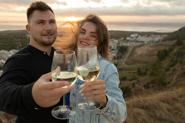 Loving couple clinking glasses of white wine at sunset