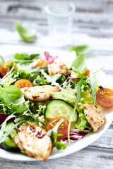 Salad with Chicken Breast, Cherry Tomatoes, Cucumber, Rocket and fresh Basil. Bright wooden background. Close up.