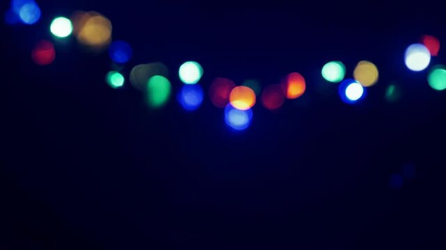 Blurred close-up of festive garlands with colorful lights decorating a fir tree
