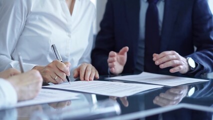 Business people wearing suits signing important documents during a corporate meeting. Win-win concept