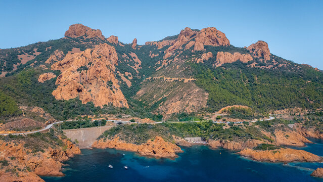 Montagnes orange du massif de l'Est&eacute;rel en drone, pr&egrave;s de Saint-Rapha&euml;l, dans le sud de la France, avec la route qui longe la c&ocirc;te.