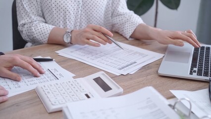 Fototapeta premium Bookkeeper woman is working with a colleague, using magnificent glass, calculator and laptop. Audit and taxes concept