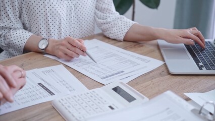 Professional female bookkeeper with a colleague are working on business finances. using calculator...