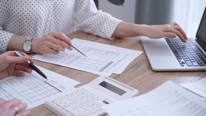 Bookkeeper woman is working with a colleague, using magnificent glass, calculator and laptop. Audit and taxes concept