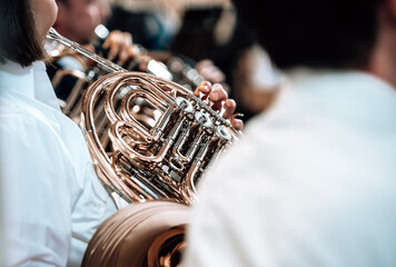 Close-up of a brass musician playing the French horn as a member of a band at a concert