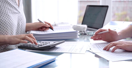 Fototapeta premium Business people, accountants or auditors reviewing financial data in office. Two professionals analyzing paper reports and using calculators. Audit and taxes