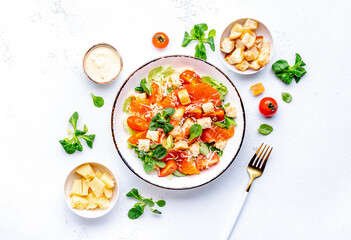 Delicious salad with salmon, iceberg lettuce, croutons, grated parmesan cheese and caesar dressing. White background, top view