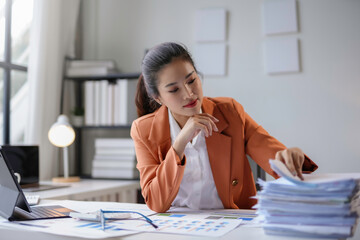 Businesswoman reviewing paperwork and financial reports, organizing documents on her desk