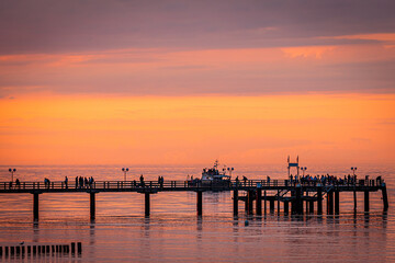 Obraz premium sunset colours on the beach contrasting the pier