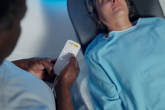 Medical professional adjusting bedside control panel in hospital room, ensuring patient's comfort and proper positioning