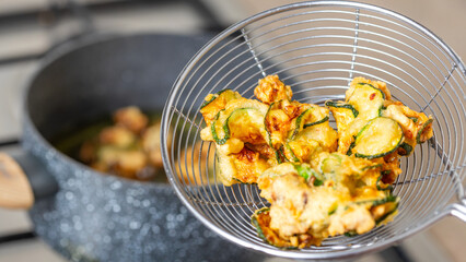 Crispy zucchini in a light batter being fried to golden perfection close-up