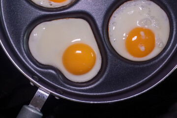 Close-up of fried eggs in a pan, with one egg shaped like a heart, highlighting the health and nutritional properties of eggs.