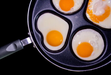 Close-up of fried eggs in a pan, with one egg shaped like a heart, highlighting the health and nutritional properties of eggs.