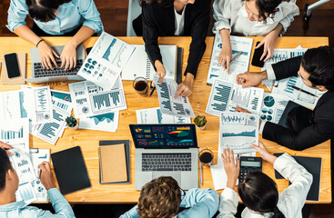 Panorama top view diverse group of business analyst team analyzing financial data report paper on meeting table. Chart and graph dashboard by business intelligence analysis. Meticulous