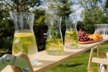 Refreshing Citrus Infused Water in Glass Pitchers on Wooden Table Outdoors