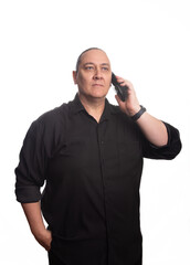 Adult man, an adult man in black clothing with cell phone in front of a white background, selective focus.