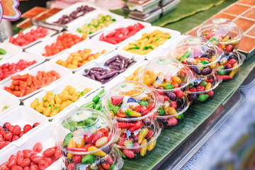 A table full of colorful fruits and vegetables, including peppers and tomatoes. The table is covered with plastic containers filled with various fruits and vegetables