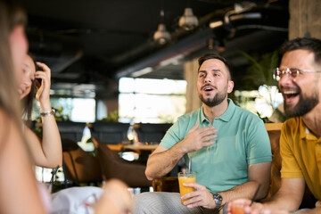 Happy friends talking during social gathering in a café.