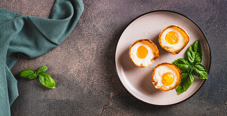 Baked egg and bacon rolls with basil on a plate on a table top view web banner
