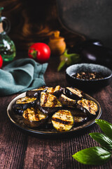 Appetizing spicy grilled eggplant pieces on a plate on the table vertical view