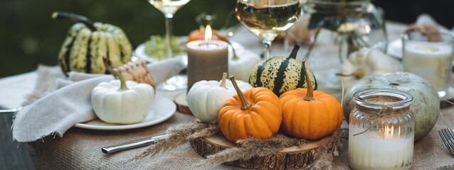 Fall table decoration with pumpkins, wine. Family thanksgiving dinner arrangement outdoors in the...