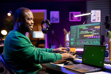 Young artist producing new tracks on daw software next to an isolated mockup screen. Sound designer...