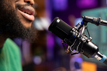 Songwriter musician composing a new track and recording it on microphone, singing aloud in his home studio and editing. Producer performing a song, acoustical engineering. Close up.