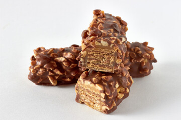Cross-section of wafer caramel bar with nuts and chocolate glaze on white table