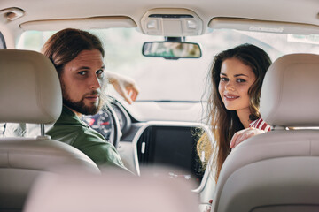 Young couple in a car looking back at the camera with smiles Soft interior lighting creates a warm and inviting atmosphere