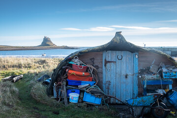 A boat shed on Holy island with Lindisfarne castle in the background 