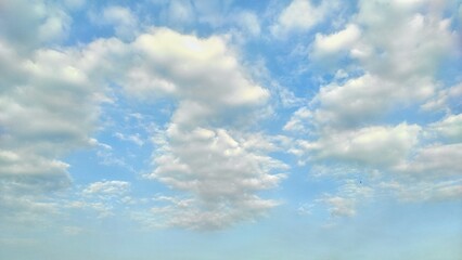 Vast blue sky dotted with soft, fluffy clouds, creating a tranquil and peaceful atmosphere. Perfect for backgrounds or serene nature themes