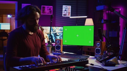 Musician playing piano midi controller and learning new notes, looking at online lesson on pc. Artist uses greenscreen display, learn to play keys on electronic keyboard. Camera B.