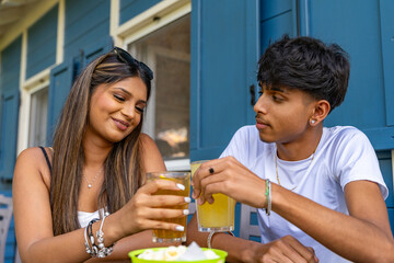 young couple toasting an aperitif sitting at a table in a rustic outdoor bar