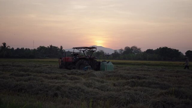 slow motion two young men farmers work hard near the tractor in a vietnam field at dusk