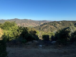 landscape photo - dirt trail in the forested mountains, rolling hills beneath a cloudless summer...