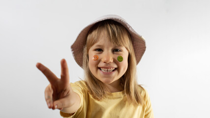 Little girl with emojis on face showing v gesture portrait
