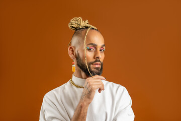Trendy black latin gay man in white clothes look camera questioning look isolated on orange...